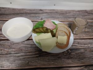 Zdjęcie przedstawia Dietę podstawową: Chleb mieszany pszenno-żytni Masło extra  Schab Kruchy z Liszek- wieprzowy, parzony, wędzony  Ser mozzarella Og&oacute;rek kiszony Sałata zielona Kawa zbożowa z mlekiem Makaron na mleku